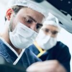 CÂNCER DE PRÓSTATA EM VILHENA: COMO REALIZAR O TRATAMENTO COM CIRURGIA ROBÓTICA EM CUIABÁ 3 urologista sentado em um console de cirurgia robótica em cuiabá